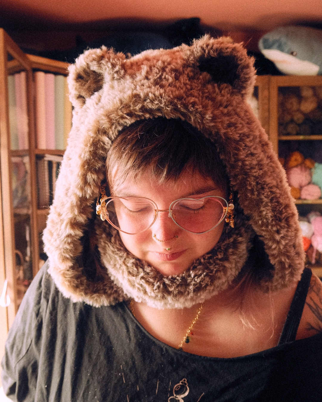 Person wearing a fluffy brown animal hood with ears, indoors.
