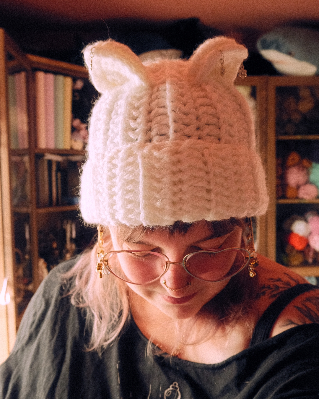 Person wearing a crochet hat with cat ears in a cozy room.