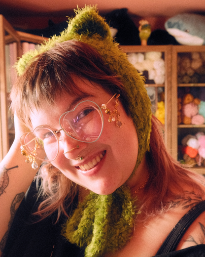 Person wearing headband style earmuff made of mossy yarn with cat ears