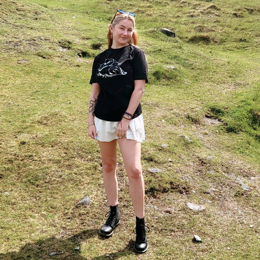 Model Cait wears a black size medium tshirt. The artwork is a white ink drawing of a fat pigeon.