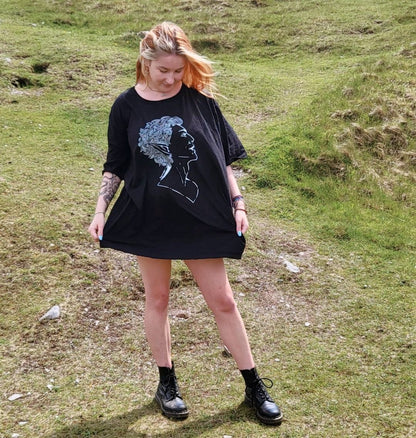 Model Cait wears a black size 4xl tshirt as an oversized tshirt dress. The artwork is a white ink portrait of Astarion from Baldurs Gate 3.