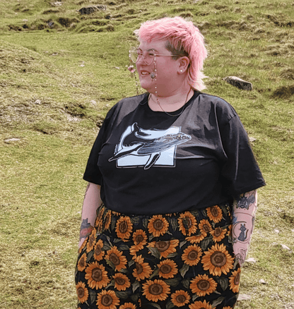 Rayn wears a black size 4xl tee with a white ink drawing of a humpback whale on it.