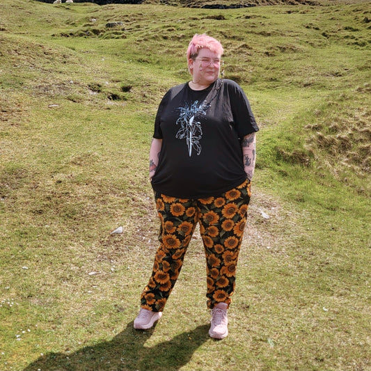 Rayn wears a black size 4xl tee with a white ink drawing of a dagger on it.